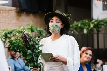 A woman wearing a mask while holding plants.