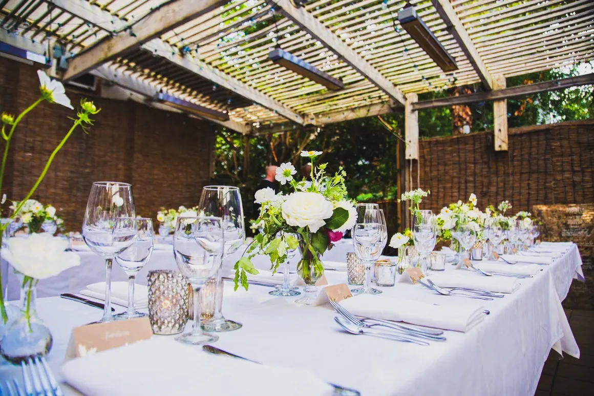 A table set for an outdoor wedding with white linens and flowers.