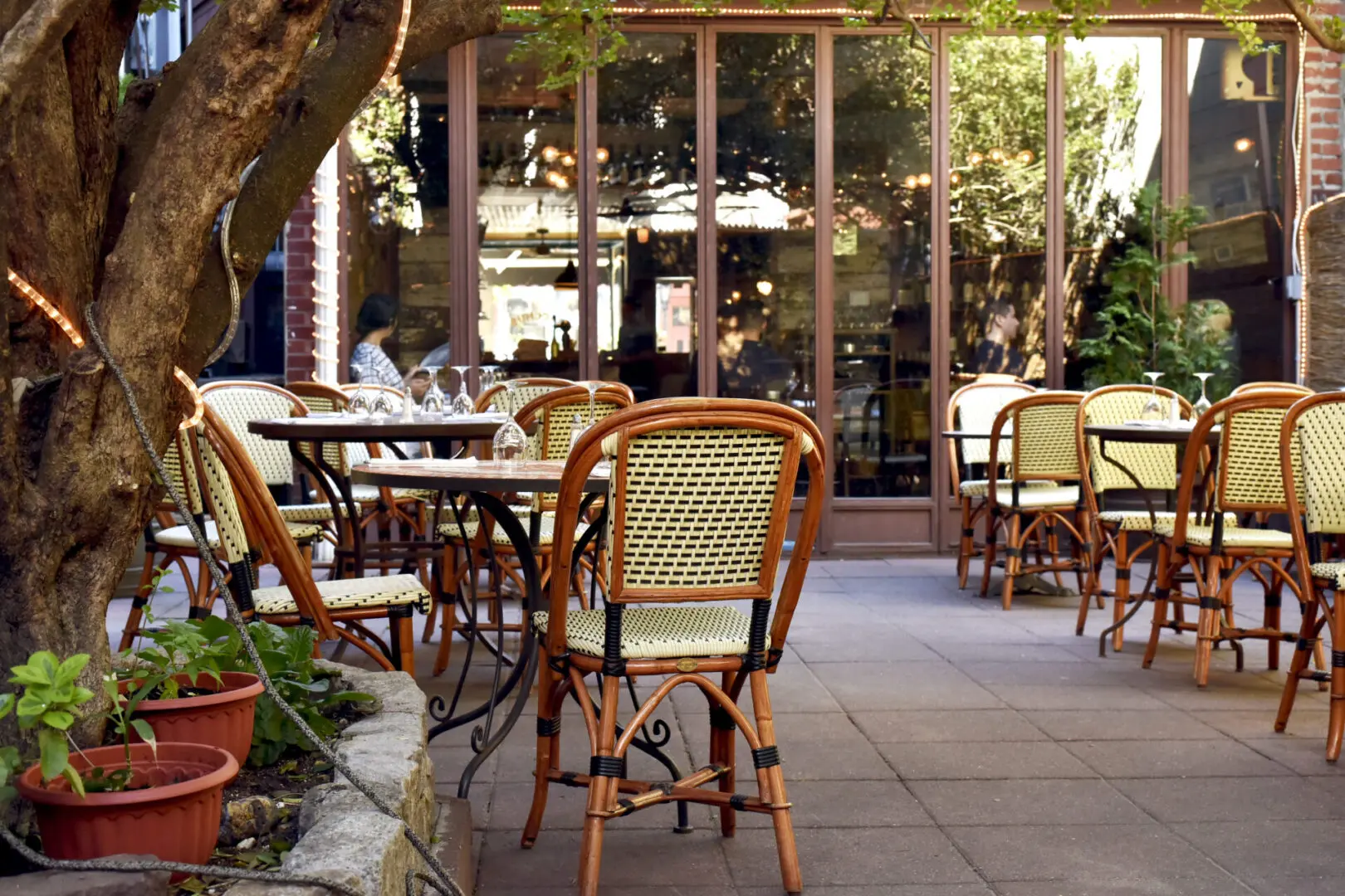 A patio with tables and chairs outside of it