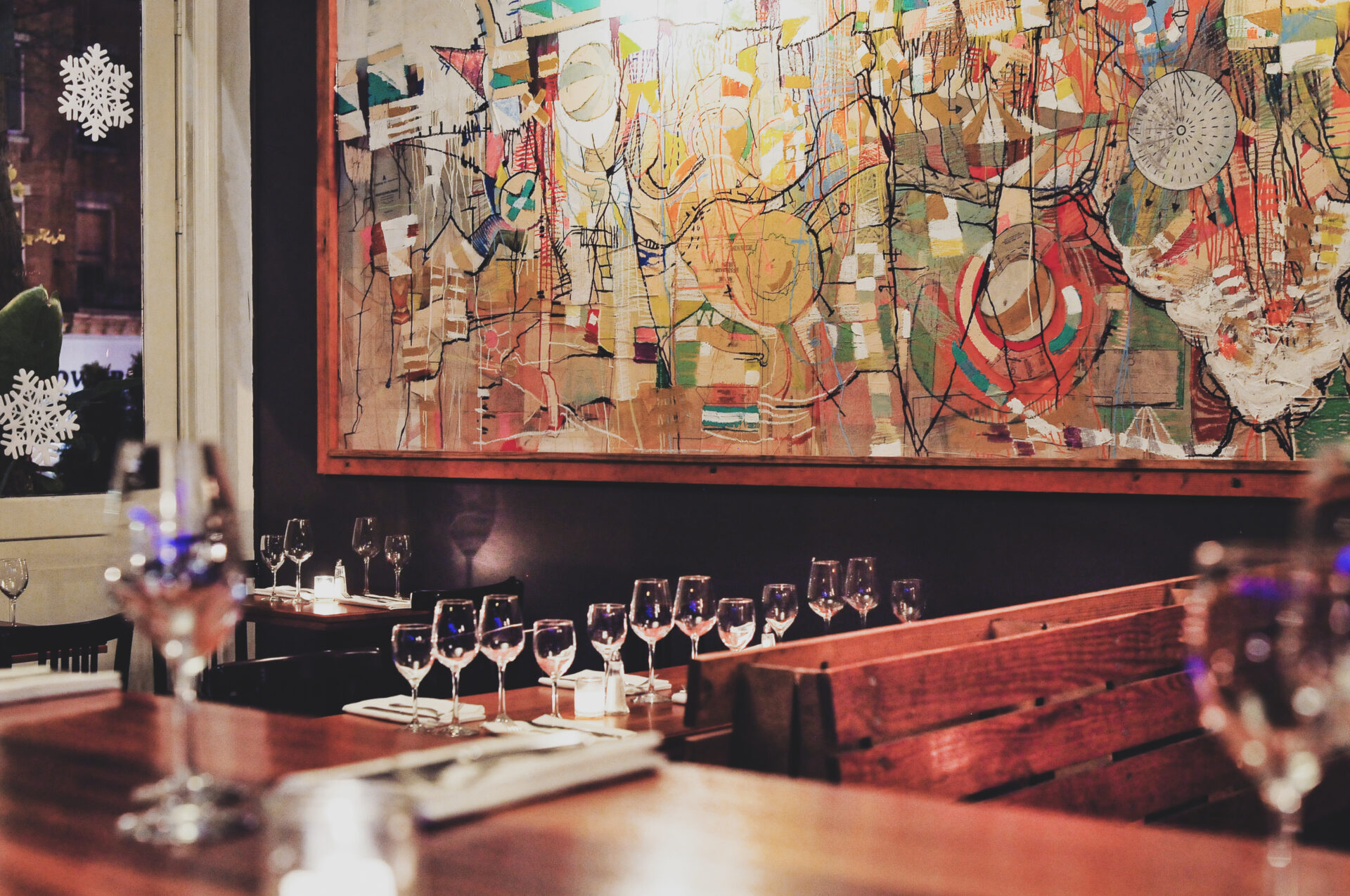 A table with wine glasses and a painting on the wall.