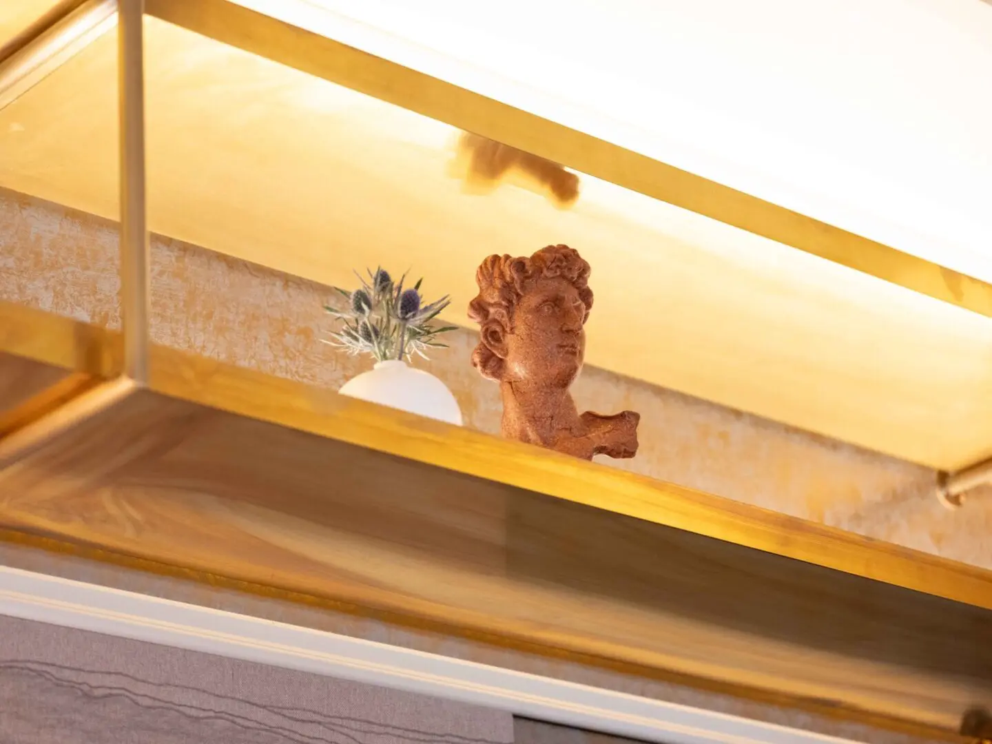 Gold shelf with statue and flowers.