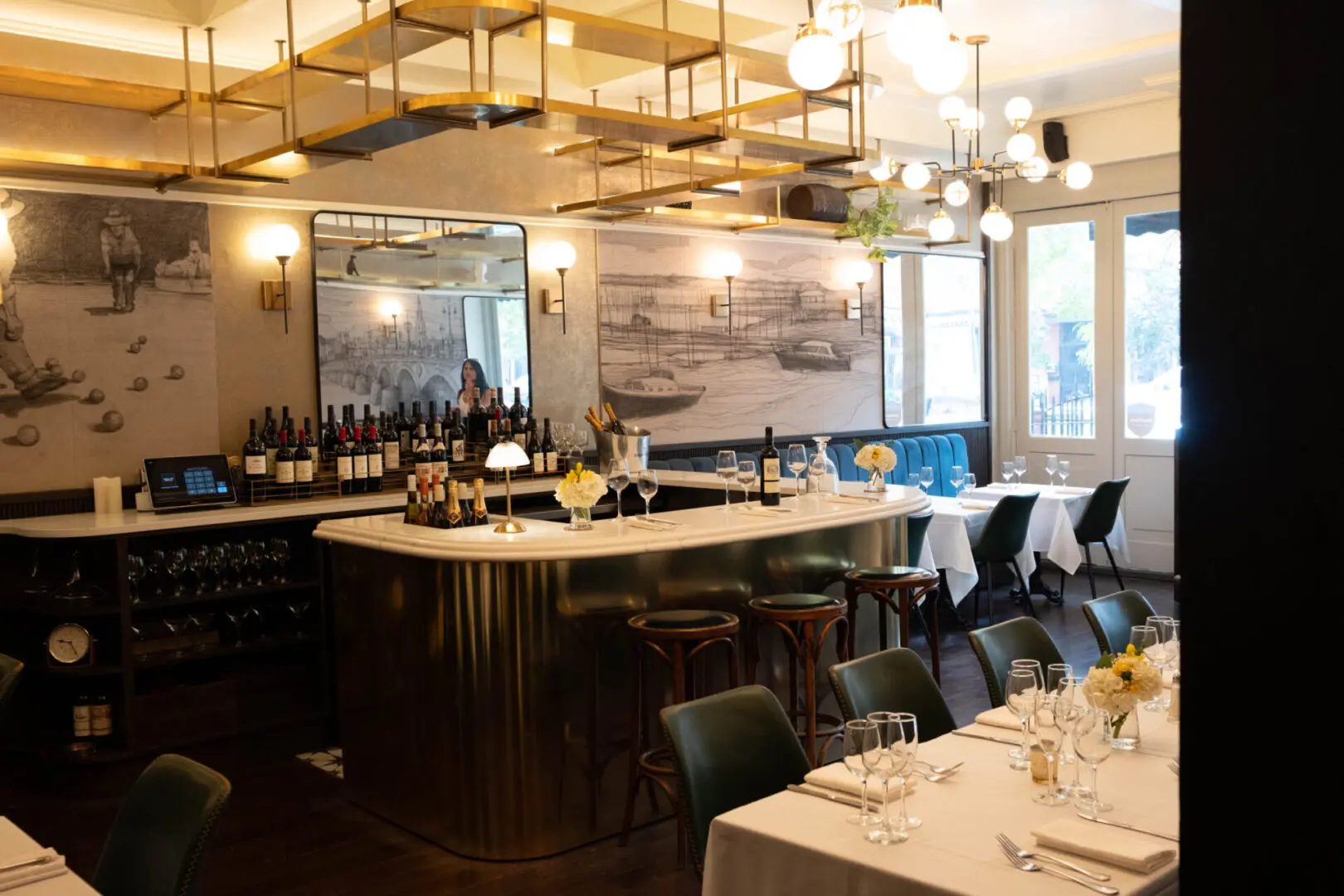 Brass bar in a restaurant with tables set.