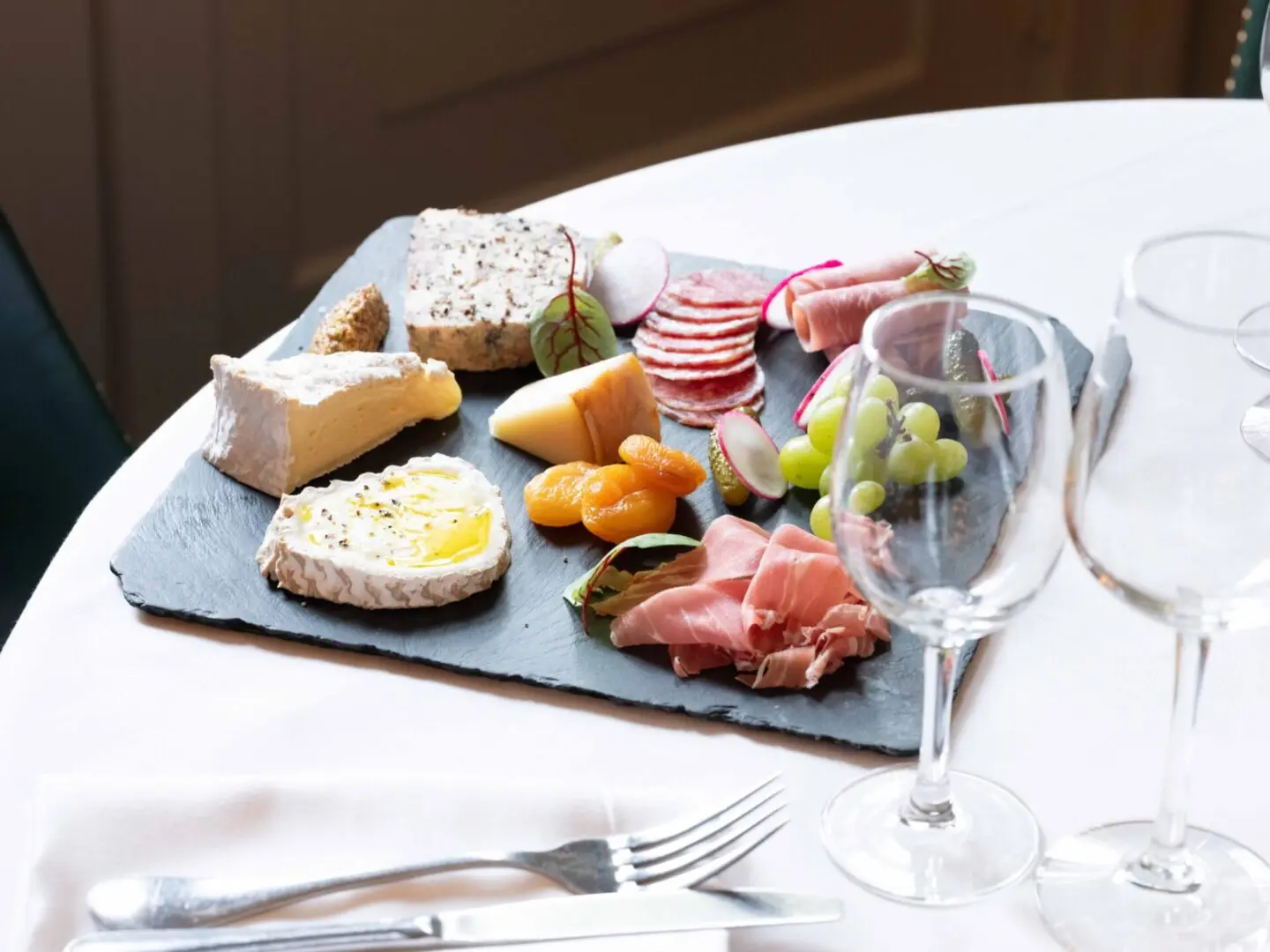 Cheese and charcuterie platter with wine glasses.